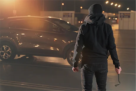 A person approaching a vehicle at night.