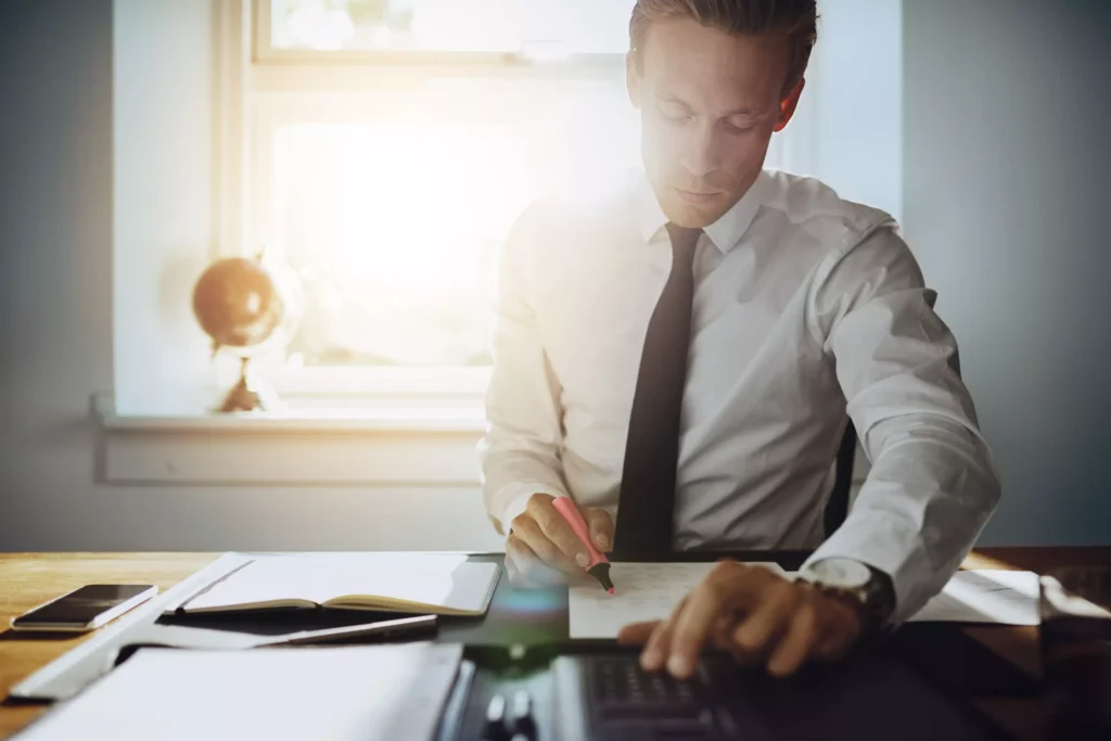 An attorney working at his desk, highlighting paper.
