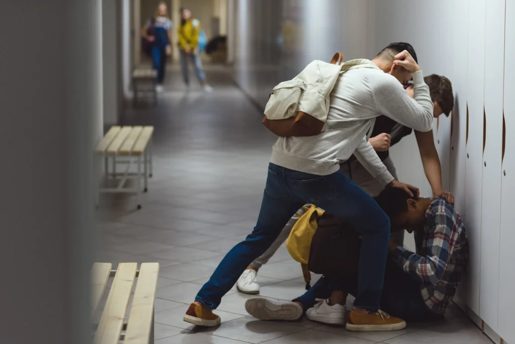 Two students assaulting another student in a school hallway.