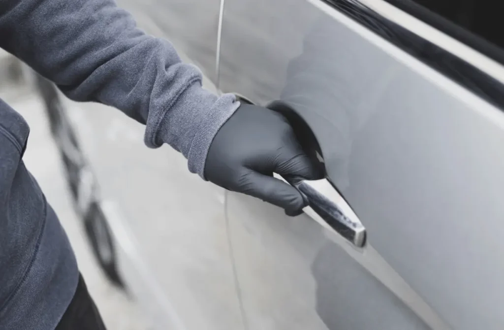Gloved hand opening a silver car door.